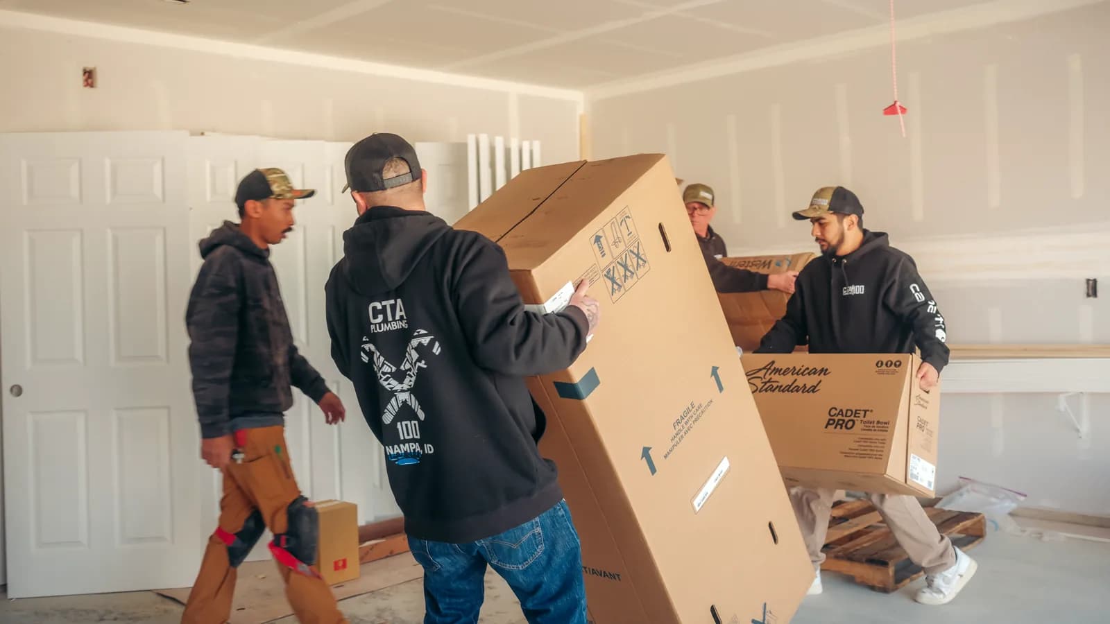 CTA Plumbing team delivering boxed plumbing fixtures at a residential project